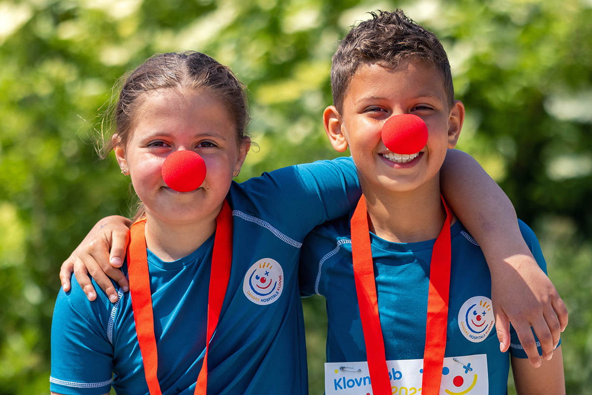 To børn med klovnenæser og medaljer står arm i arm til Klovneløb