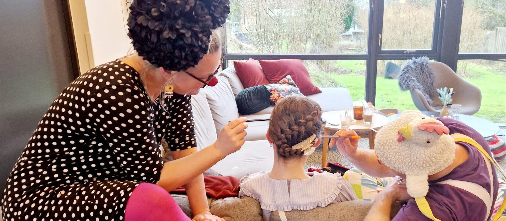 To hospitalsklovne sidder i og på en sofa ved siden af en pige med ryggen til.