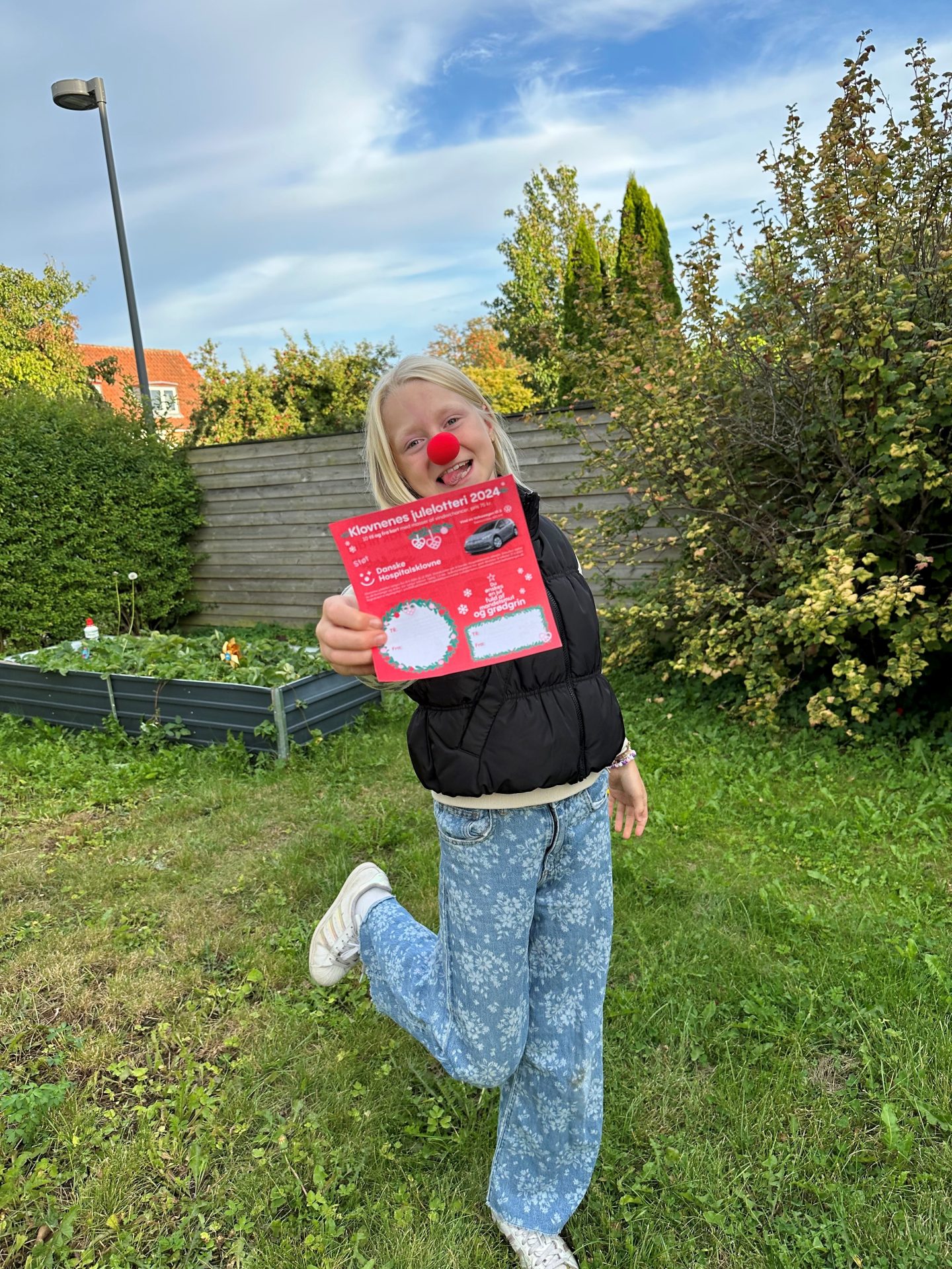 Pige står med klovnenæse på og julelotteri i hånden