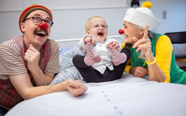 En lille pige ved navn Agnes i en hospitalsseng. Hun holder fast i sine fødder og griner stort. Ved siden af hende sidder de to hospitalsklovne, Petunia og Turbo.