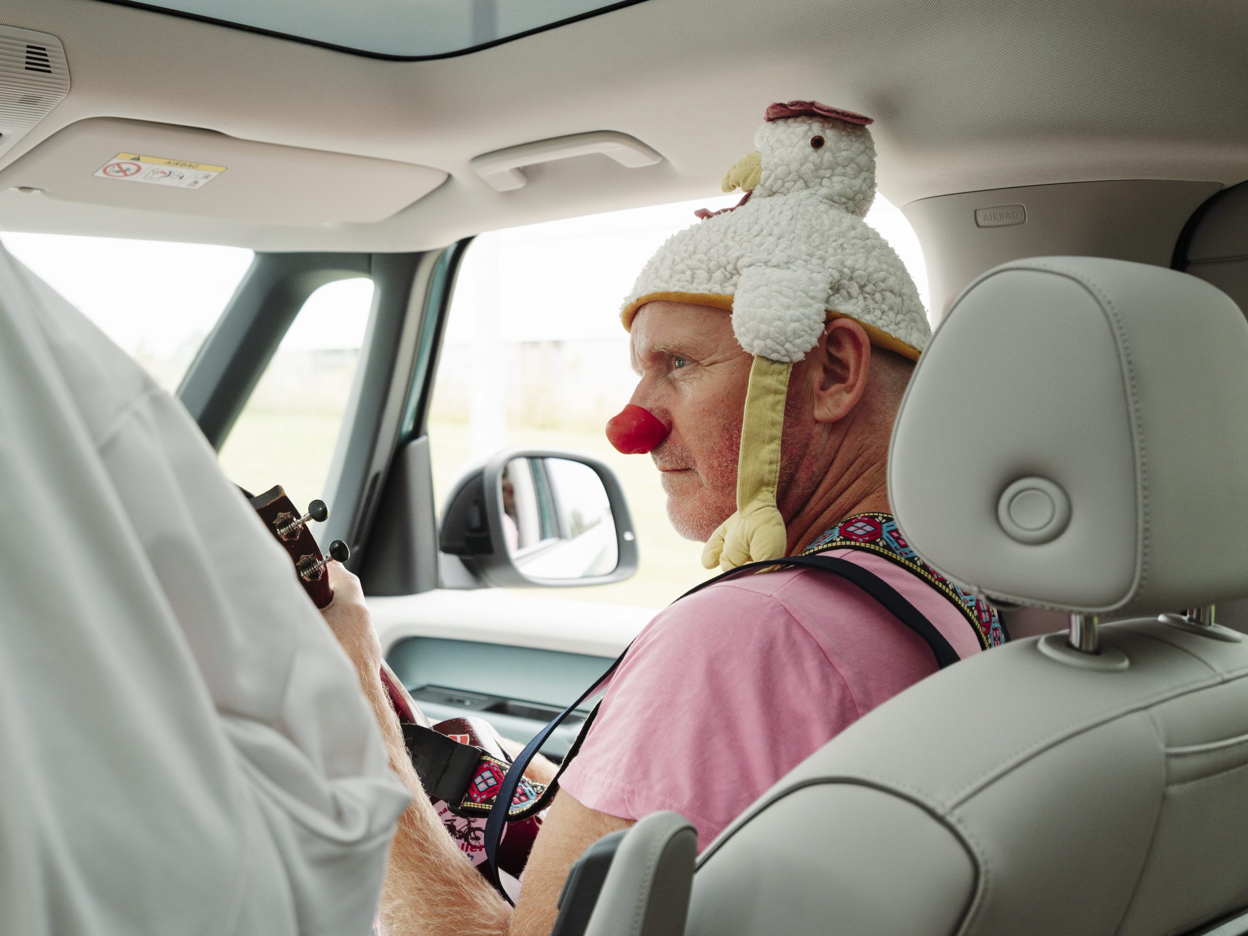 En hospitalsklovn sidder på passagersædet i klovnbulancen