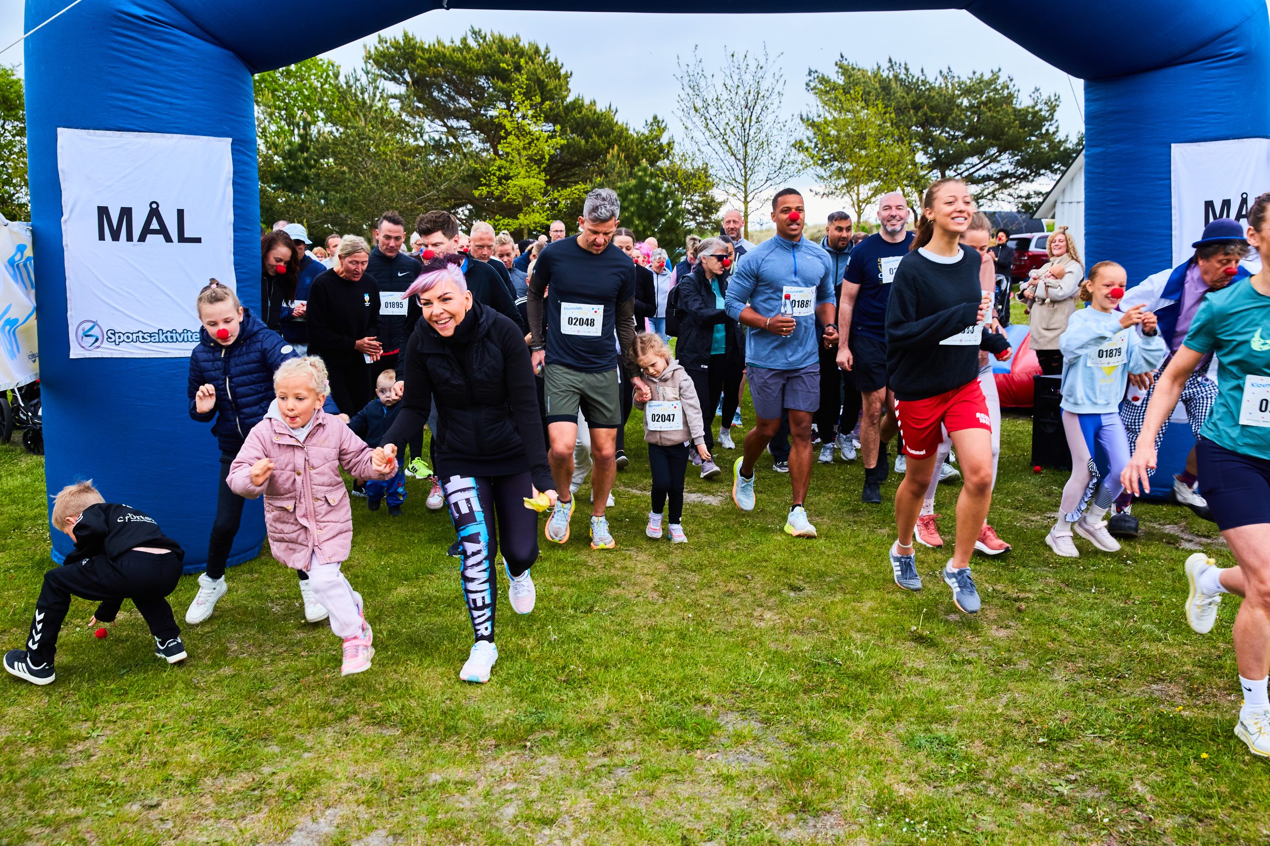 Målområde til Klovneløb. Mange glade løbere løber fra målområdet ved klovneløbet.